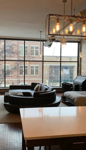 Industrial loft interior with exposed brick and floor-to-ceiling windows overlooking downtown