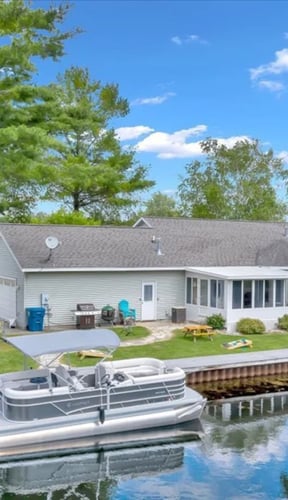 Lakefront home with pontoon boat, yard, and dock on a Michigan lake